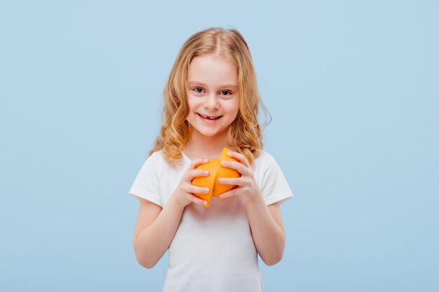 Menina feliz com uma laranja na mão