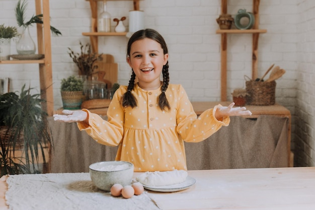 menina feliz cozinha uma torta na cozinha em um vestido de algodão