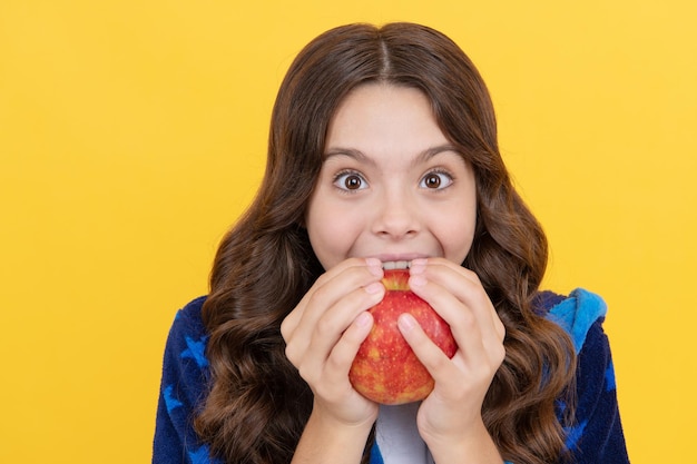 Menina feliz criança dentuça morder maçã fresca em um roupão aconchegante, estomatologia infantil.