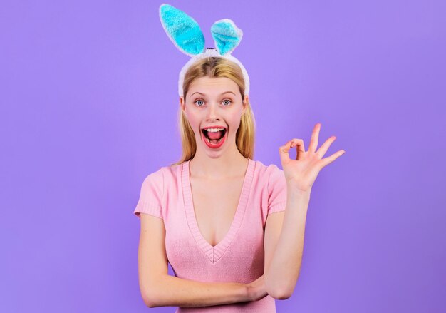 Menina feliz da páscoa mostrando sinal de mulher sorridente em orelhas de coelho com gesto okey férias de primavera