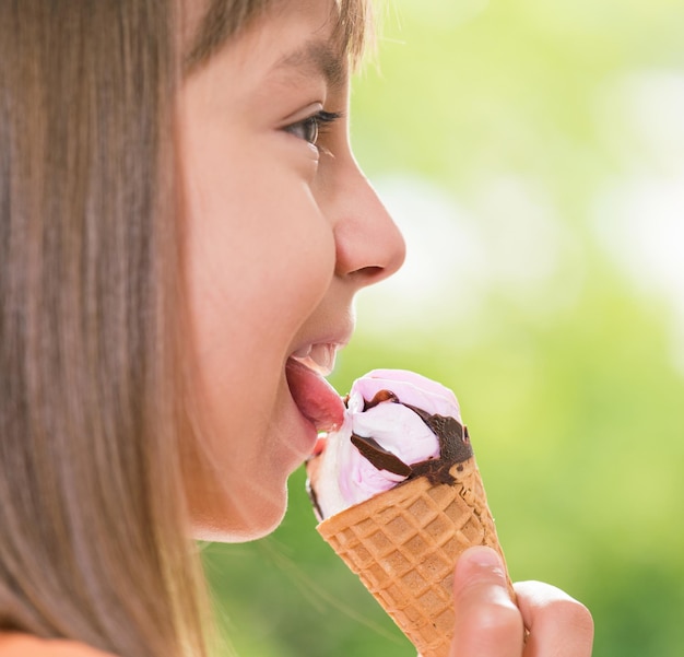 Menina feliz de 1011 anos comendo um cone de sorvete Retrato ao ar livre