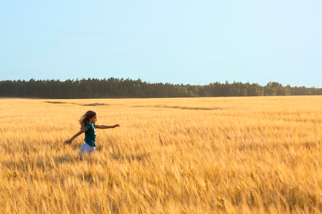 Menina feliz de 9 anos correndo em cereais mal campo fundos da natureza com espaço de cópia grátis