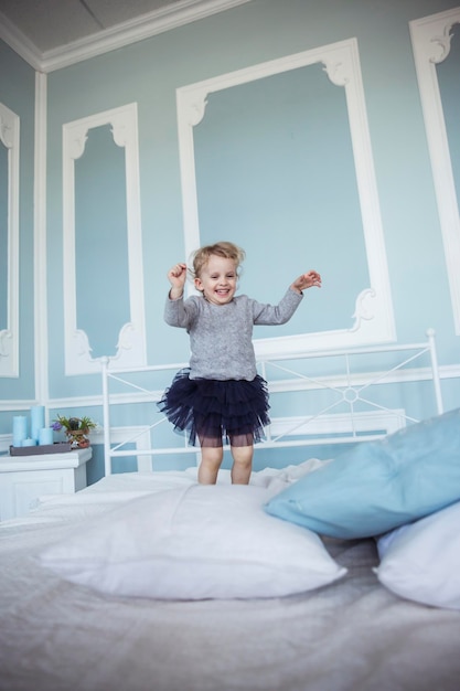 menina feliz de cinco anos pulando na cama