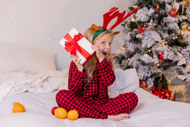 menina feliz de pijama em casa se alegra e desembala presentes para o Natal. Foto de alta qualidade