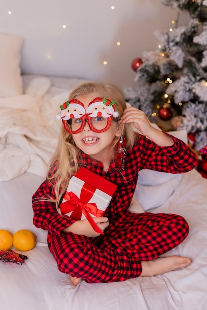 menina feliz de pijama em casa se alegra e desembala presentes para o Natal. Foto de alta qualidade