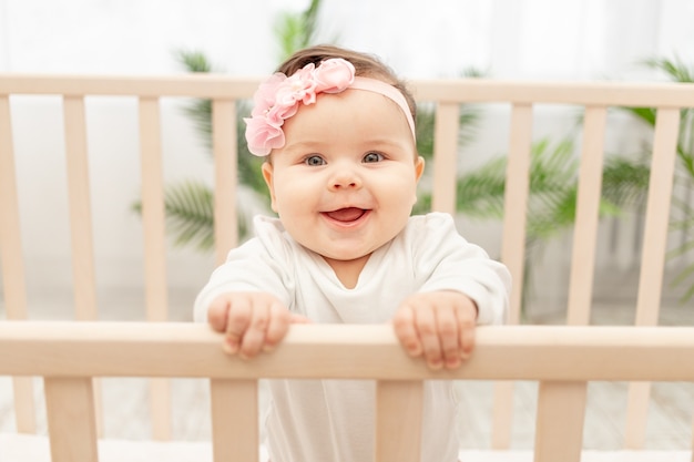 Menina feliz de seis meses parada no berço