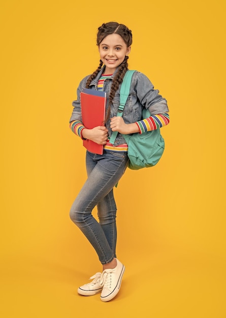 Menina feliz de volta à escola Menina adolescente segurando livros escolares fundo amarelo Educação escolar