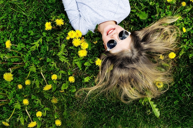 Menina feliz deitada na grama verde no verão