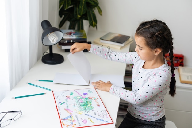 menina feliz e fofa escrevendo algo no caderno