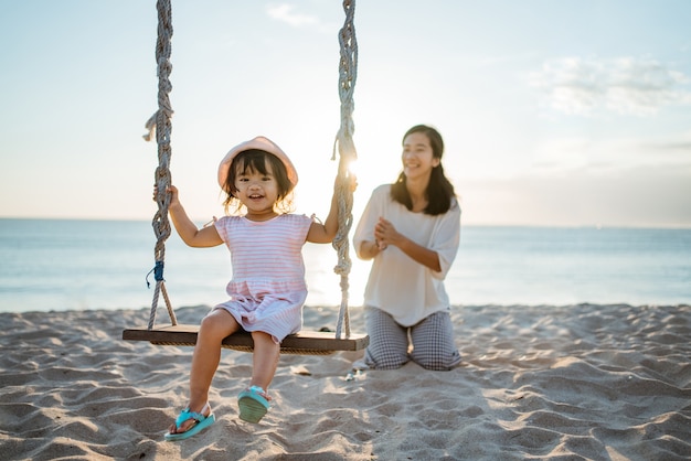 Menina feliz e mãe balançando na praia