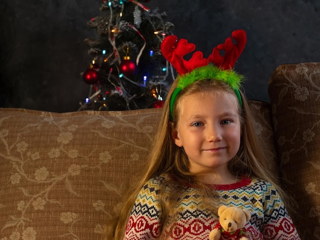 Menina feliz em chifres de veado ri parece câmera em casa retrato Sorrindo criança desdentada engraçada Ano Novo Natal