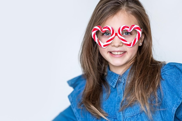 Foto menina feliz em óculos de caramelo olha para a câmera com corações e sorrisos fundo do dia dos namorados copiar espaço para texto