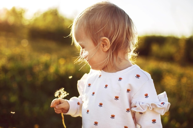 menina feliz em um campo com um dente de leão na mão