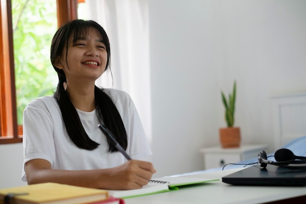 Menina feliz estudando com laptop em casa