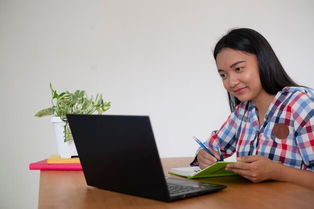 Menina feliz estudando com laptop em casa