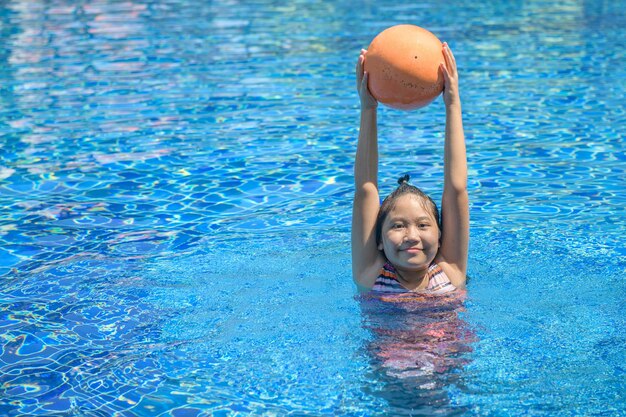 Foto menina feliz jogando bola na piscina recreação e lazer no conceito de férias