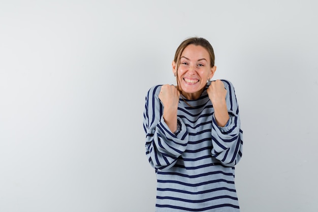 Menina feliz, levantando os punhos no fundo branco