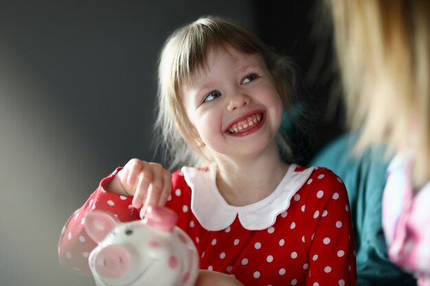 Menina feliz no vestido vermelho segurar a moeda de prata na mão