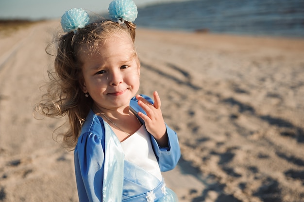 Menina feliz num vestido azul na praia