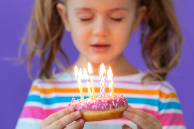 Menina feliz para seu aniversário faz desejo e sopra velas no bolo