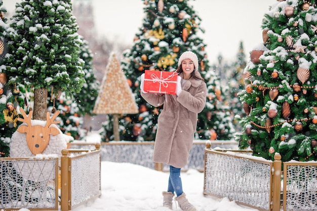 Menina feliz perto de ramo de abeto na neve pelo ano novo.