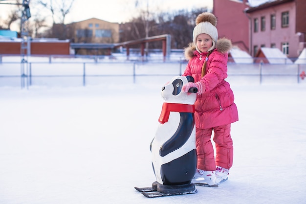 Menina feliz que aprende a patinar na pista