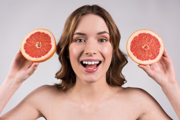 Menina feliz que levanta com a toranja isolada.