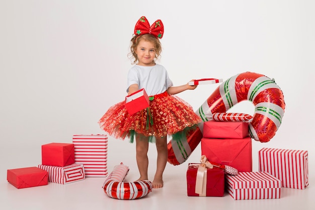 Foto menina feliz rodeada de elementos natalinos