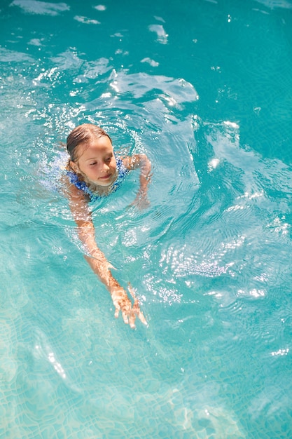 Menina feliz se divertindo na piscina, mergulhos e nadar, férias de verão em casa, resort tropical de férias.