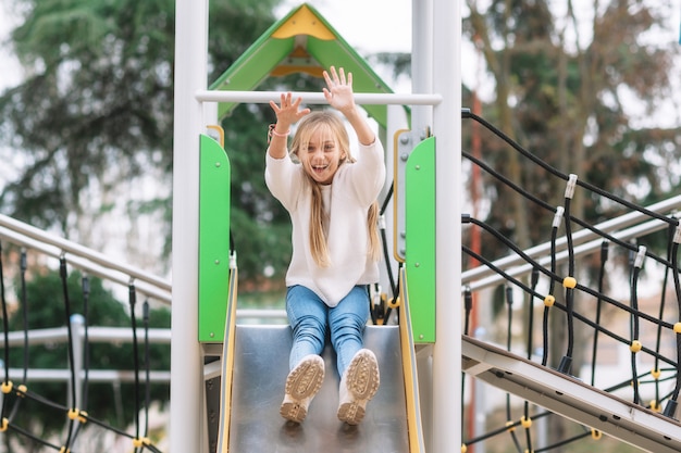 Menina feliz se divertindo no slide no parque.