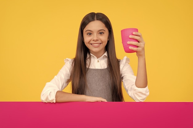 Menina feliz segura copo de plástico com bebida e placa de publicidade para bebida de espaço de cópia