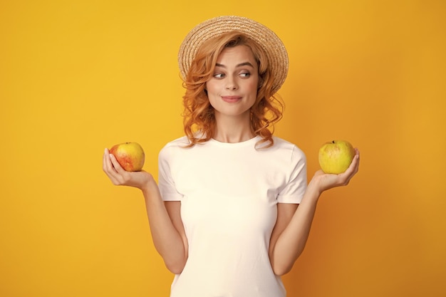 Menina feliz segurando maçã isolada sobre fundo amarelo Retrato de uma mulher bonita com uma maçã fechada