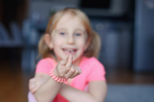 Menina feliz sorridente de seis anos segurando um primeiro dente caído e olhando para ele