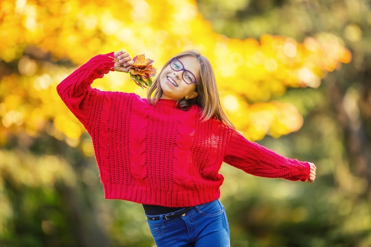 Foto menina feliz, sorridente e alegre, segurando as folhas de outono.