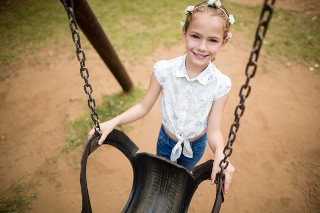 Menina feliz sorrindo enquanto segura um balanço no parque