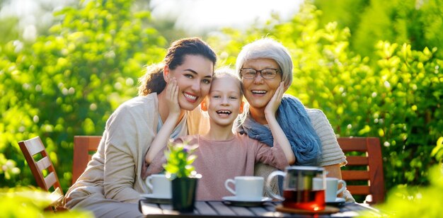 Menina feliz sua mãe e avó bebendo chá na manhã de verão