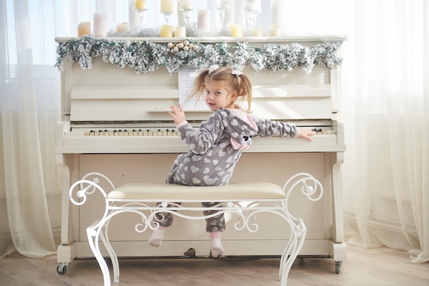 Menina feliz tocar piano no dia de natal