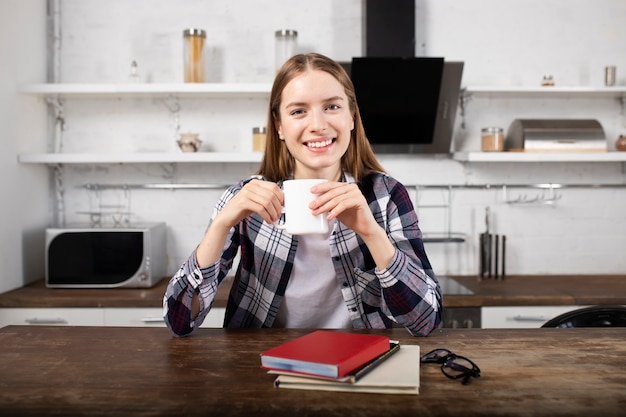 Menina feliz tomando café e lendo um livro pela manhã