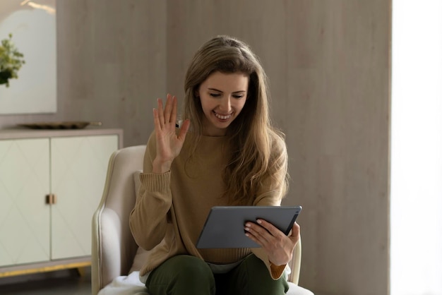 Foto menina feliz usando um tablet digital para ter aulas de línguas on-line sorrindo e segurando um computador