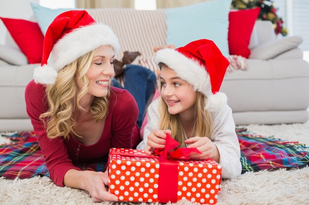 Menina festiva abrindo um presente com a mãe