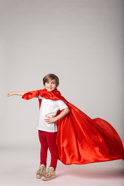 Menina fingindo ser supermulher com capa vermelha