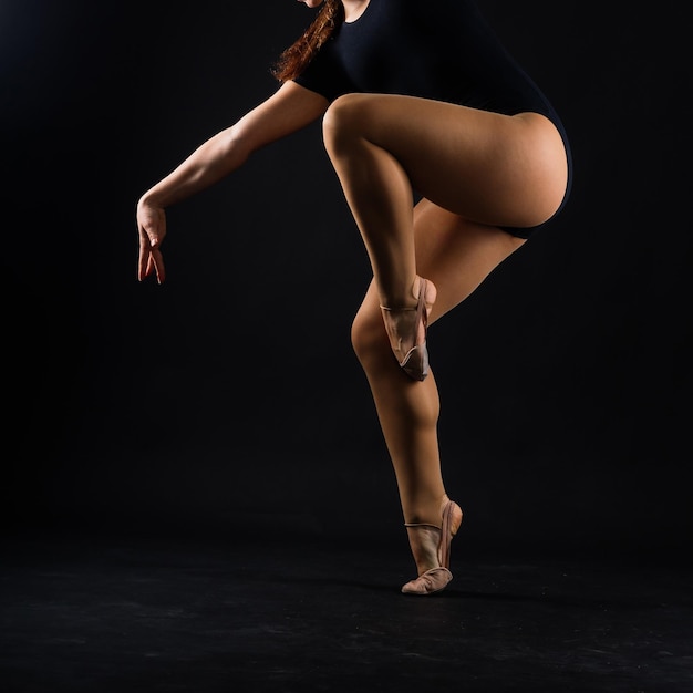 Menina flexível artista de ginástica rítmica pulando na graça de fundo branco escuro em ação de movimento