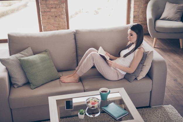 Foto menina focada mentira divã lendo livro didático