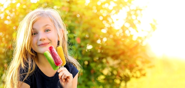 Menina fofa e feliz com picolés congelados coloridos