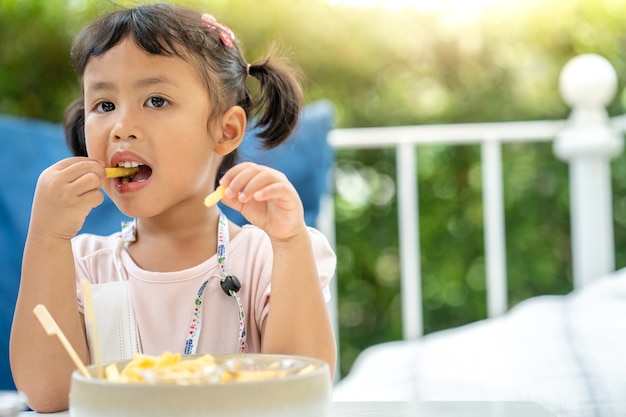 Menina fofa gosta de comer batatas fritas no almoço ao ar livre