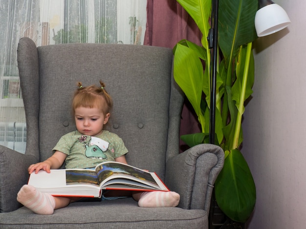 Menina folheando um livro sentada em uma cadeira, estilo de vida