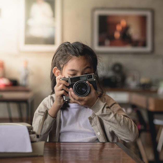 Menina fotografando com câmera em uma mesa em um café
