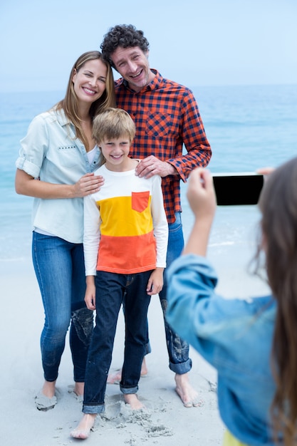 Menina fotografando família feliz na beira-mar