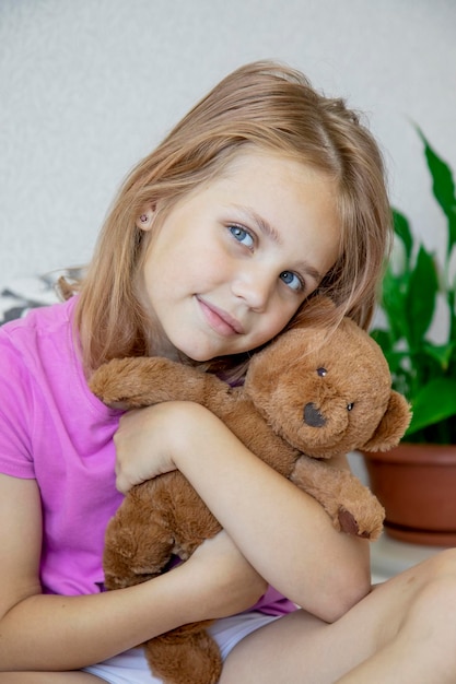 menina gentilmente abraça seu ursinho marrom