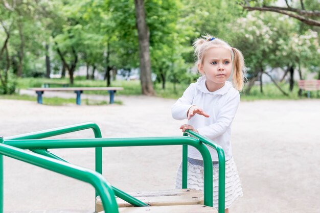 Menina gira o carrossel para passear no playground